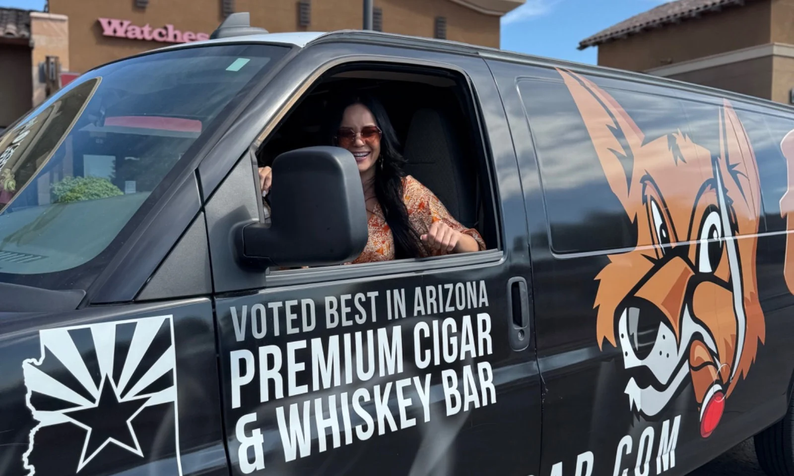 A smiling guest at the wheel of the Fox Cigar Bar van, wrapped with the fox logo