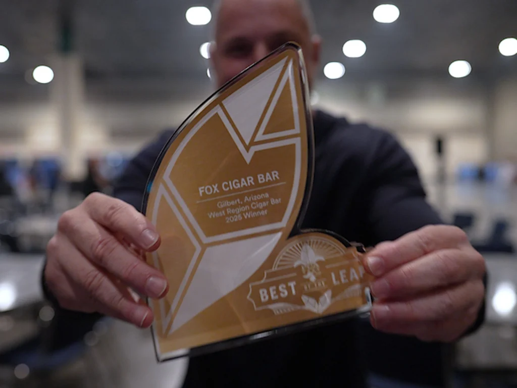 A man holds the gold Best of the Leaf award for Fox Cigar Bar Gilbert, West Region Cigar Bar 2025 winner