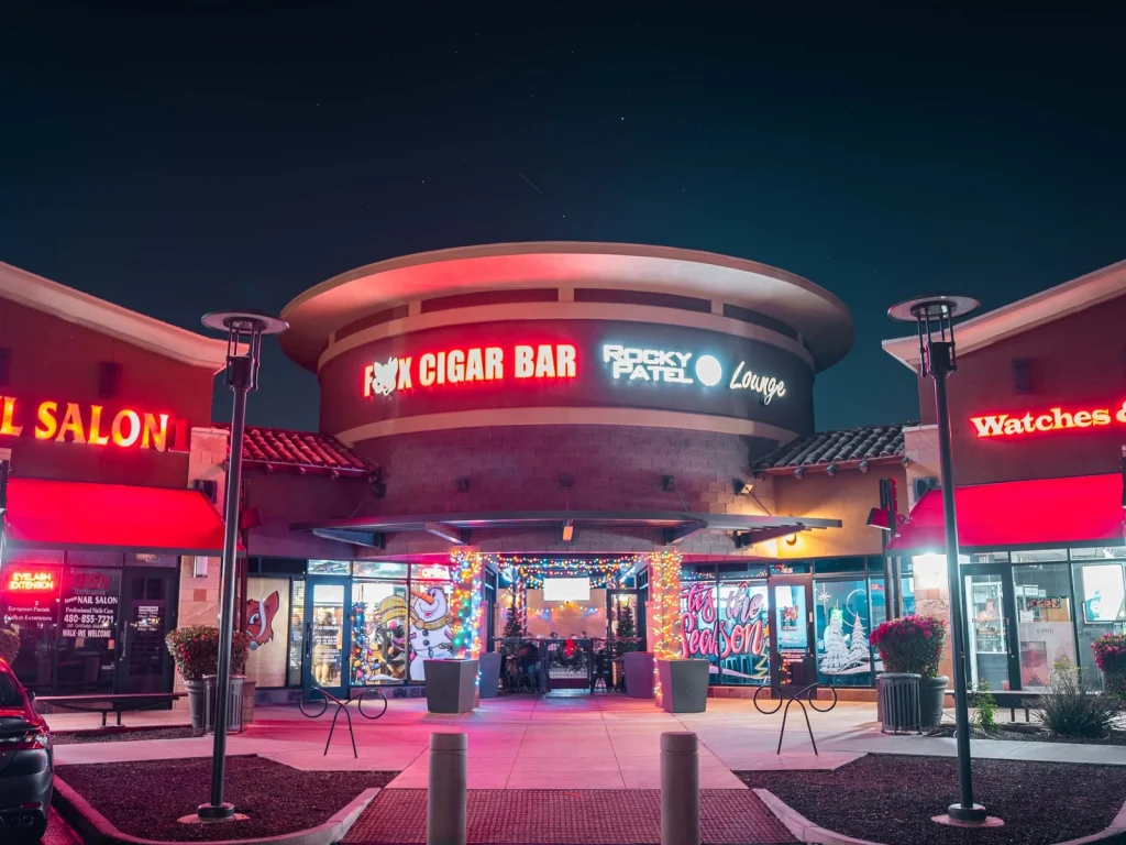 Fox Cigar Bar Gilbert storefront at night with red neon signage, holiday lights and a lit entrance patio under a starry sky