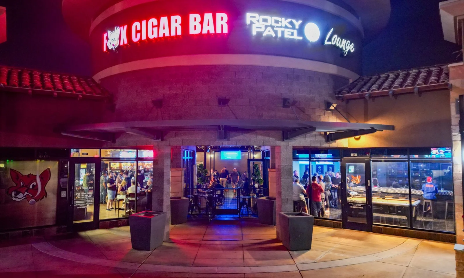 Fox Cigar Bar Gilbert at night, the red sign lit above an open front full of guests