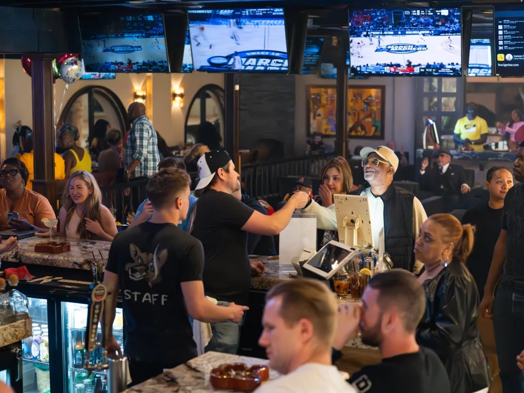 Guests and staff crowd the main bar at Fox Cigar Bar Scottsdale on game day, March Madness on TVs overhead