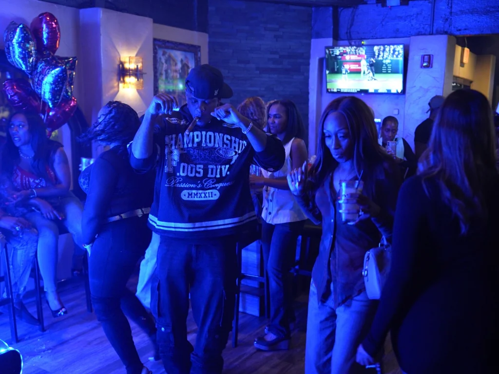 Guests dance under blue lighting at a party night inside Fox Cigar Bar Scottsdale, balloons and a TV in the background
