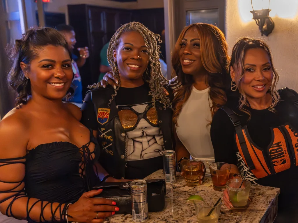 Four women smiling around a granite high-top table with cocktails at Fox Cigar Bar Scottsdale