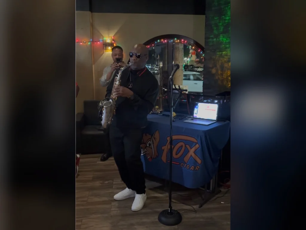 Saxophonist performing live at Fox Cigar Bar Scottsdale beside a table with a Fox Cigar banner