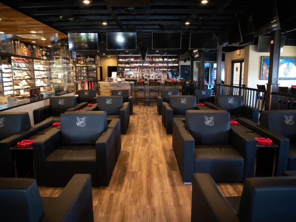 Rows of black leather lounge chairs with fox logos lead toward the bar and cigar humidor at Fox Cigar Bar Scottsdale