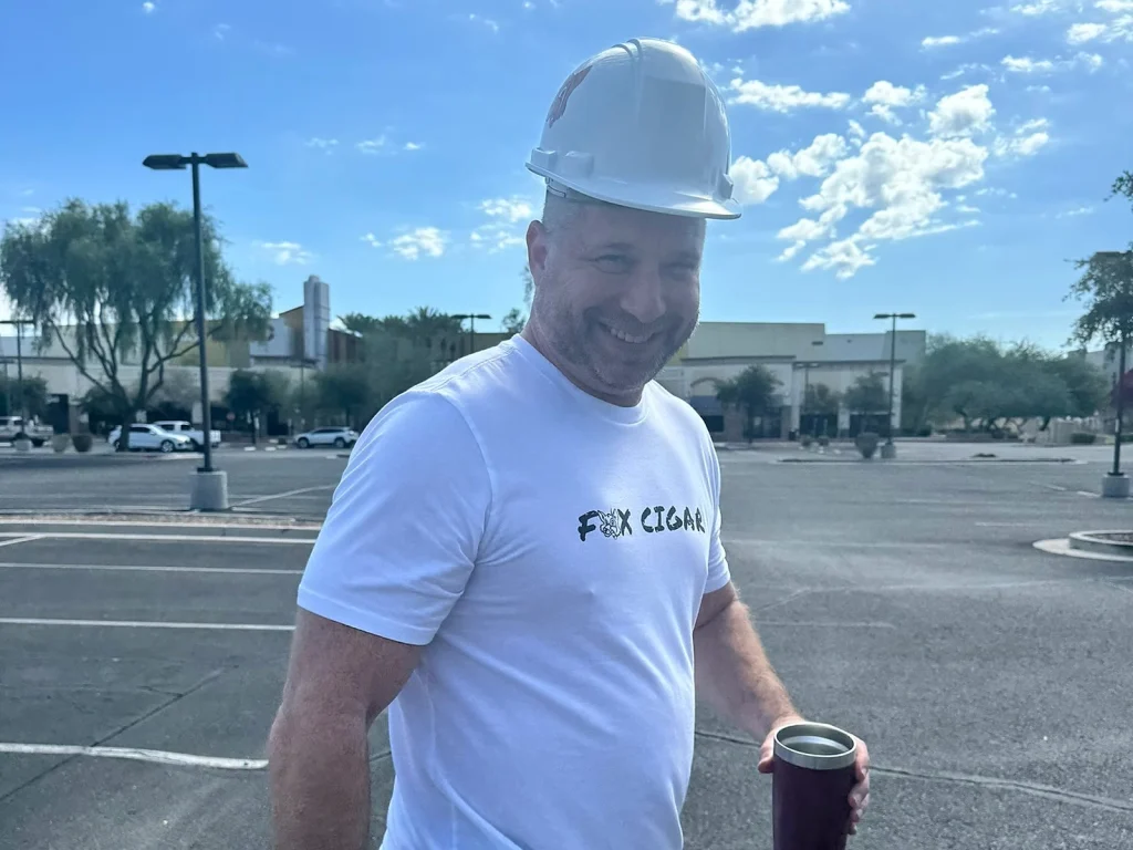 A Fox Cigar team member in a hard hat outside the Surprise site on a clear Arizona morning