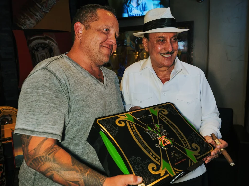 A guest shows off a collectible OpusX 25 Years Celebration humidor alongside Carlito Fuente.
