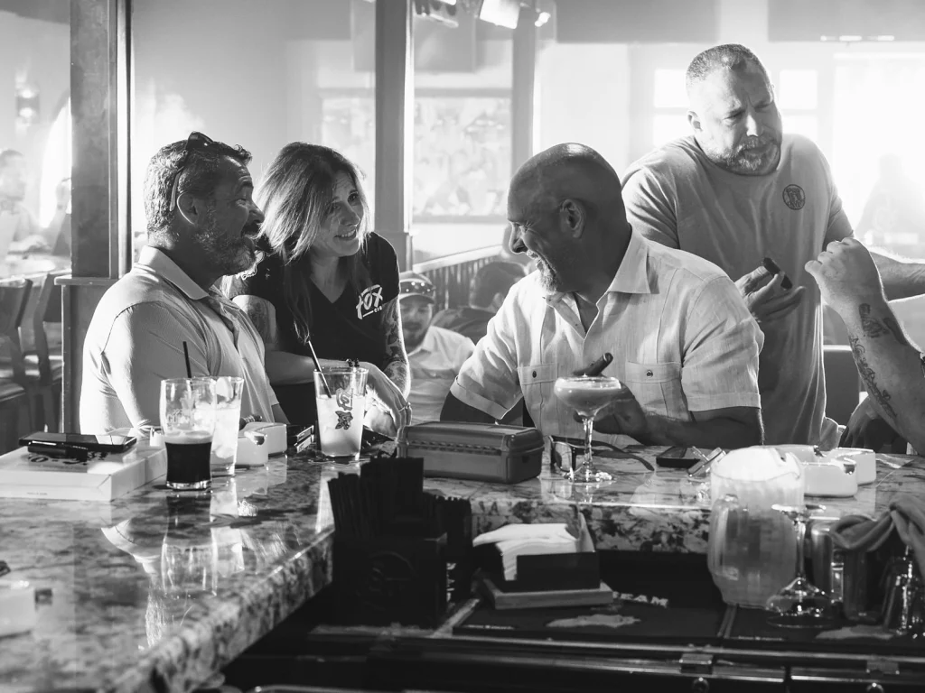 Guests talking over cigars and drinks at the bar in a Fox Cigar Bar lounge